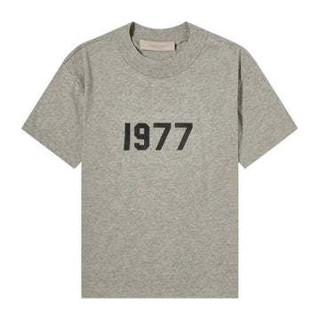 Fear of God Essentials 1977 Dark Oatmeal Tee z czarnym nadrukiem "1977" na piersi.