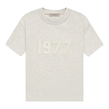 Jasna koszulka Fear of God Essentials 1977 w kolorze Light Oatmeal z wytłoczonym napisem "1977".