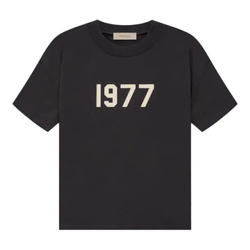 Fear of God Essentials 1977 Iron Tee, ciemnoszara koszulka z białym napisem "1977" na przodzie.