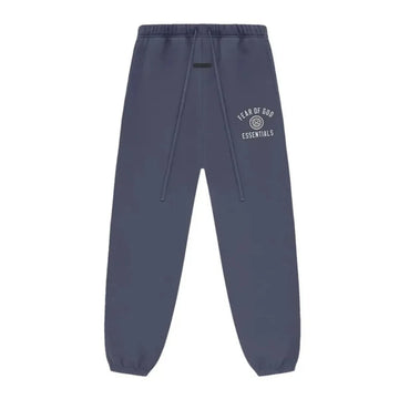 Fear of God Essentials Marine Fleece Sweatpant w granatowym kolorze, z białym logo i ściągaczami.